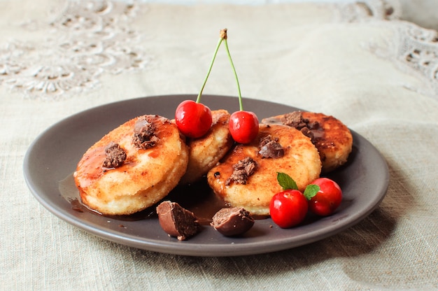 Hüttenkäsepfannkuchen mit Kirschen und Schokolade in einer braunen Platte.