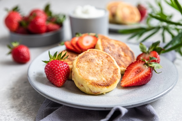 Hüttenkäsepfannkuchen oder Krapfen mit Erdbeere und Naturjoghurt