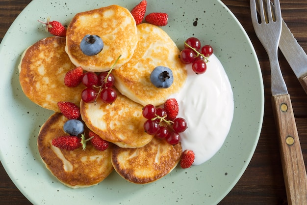 Hüttenkäsepfannkuchen, Syrniki mit frischen Beeren zum Frühstück