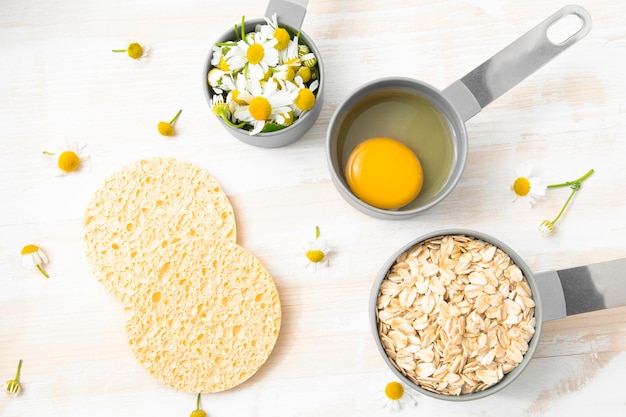 Huevo de avena con flores de manzanilla en cucharas medidoras para una mascarilla corporal casera