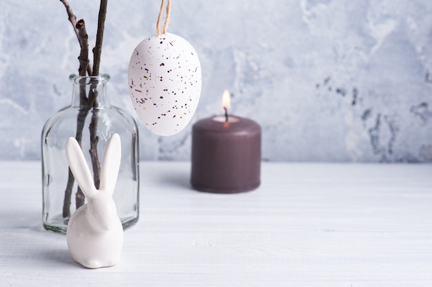 Huevo blanco y conejito en rústica composición de Pascua en mesa de madera blanca