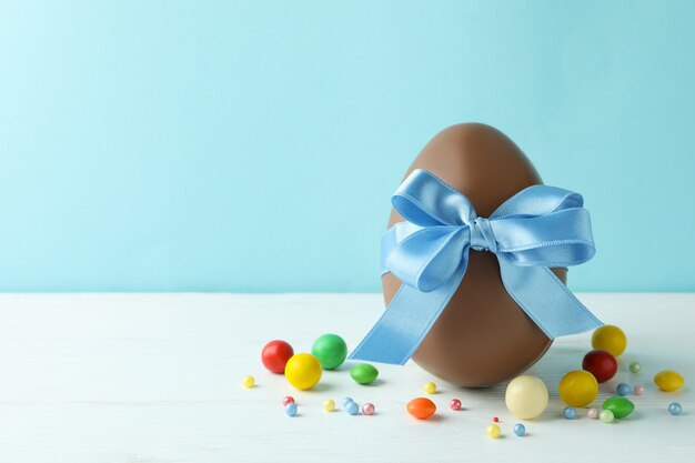 Huevo de chocolate de Pascua y dulces en mesa de madera blanca