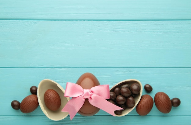 Foto huevo de chocolate de pascua con lazo de cinta rosa sobre fondo azul.