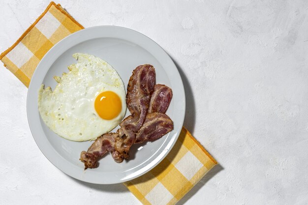 Huevo frito casero con tocino. Desayuno tradicional británico en la luz del sol