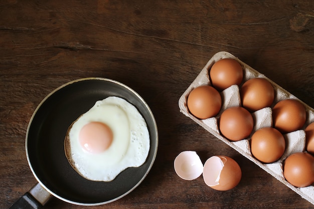 Huevo frito y huevos en la mesa de madera.