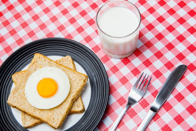 Huevo frito y pan tostado servido con leche