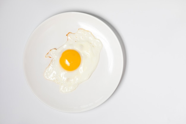 Huevo frito en un plato blanco, aislado en blanco