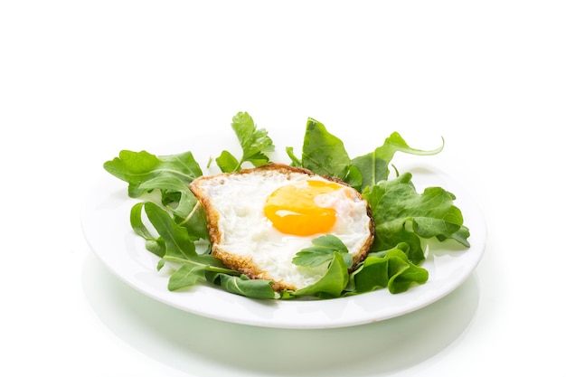 Un huevo frito con rúcula y lechuga en un plato