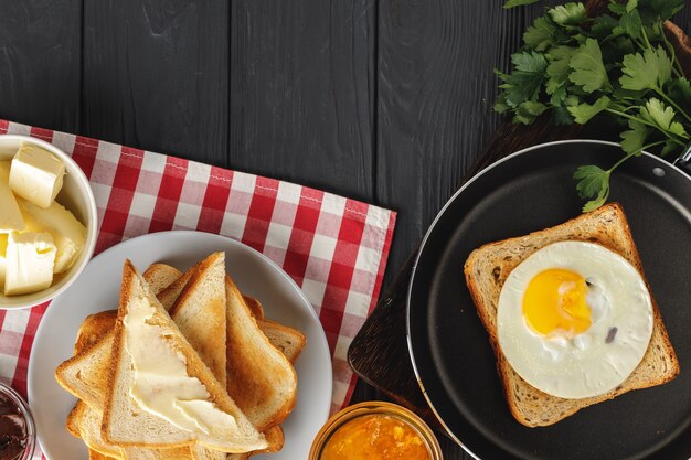 Huevo frito en sartén con pan rebanado en mesa de madera