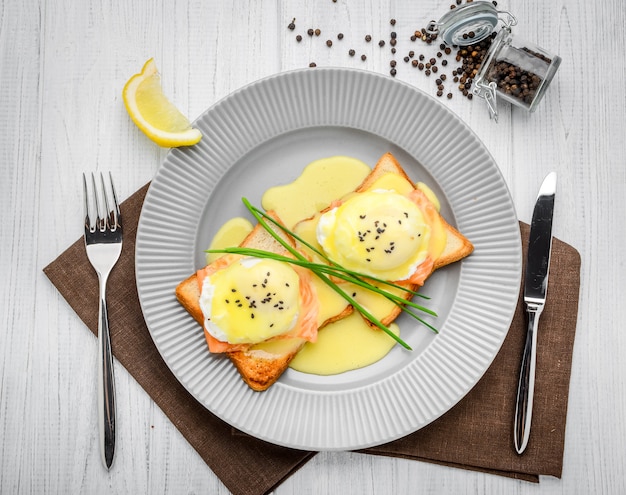 Huevo frito sobre pan para el desayuno en plato y mesa rústica, con salmón