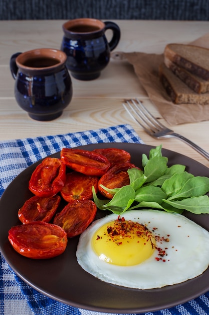 Huevo frito con tomate y ensalada de rúcula