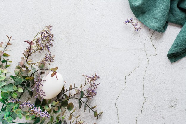 Huevo de gallina blanca en ramas de eucalipto y gypsophila sobre un fondo de textura ligera Respetuoso con el medio ambiente feliz pascua Vista superior