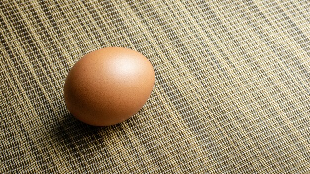 Huevo de gallina marrón sobre estera de bambú