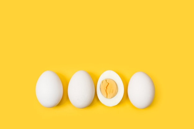 Huevo a la mitad y tres huevos aislado sobre un fondo amarillo