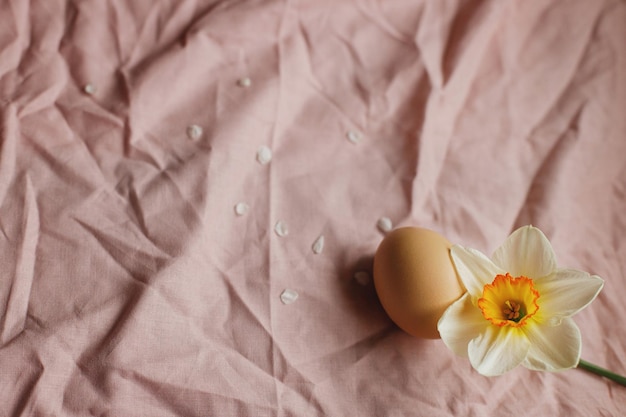 Huevo natural y flor de narcisos en fondo de tela rosada Feliz Pascua Pascua rústica