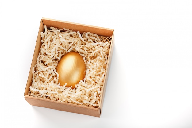 Huevo de oro en una caja de madera. El concepto de exclusividad y superprecio. Composición minimalista.