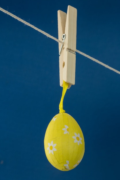 Huevo de Pascua amarillo colgando de la línea sobre fondo azul