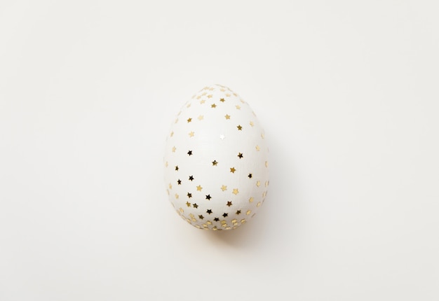 Huevo de Pascua blanco con estrellas de brillo aisladas sobre fondo blanco