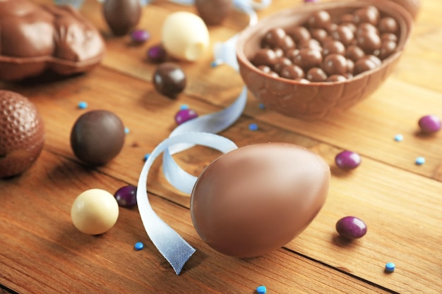 Foto huevo de pascua de chocolate con dulces sobre fondo de madera