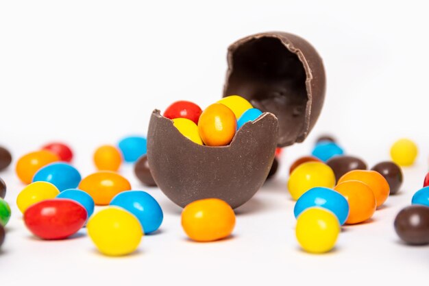 Huevo de pascua de chocolate roto con decoraciones de dulces de colores sobre un fondo blanco con dulces de colores Dulce tradición de Pascua