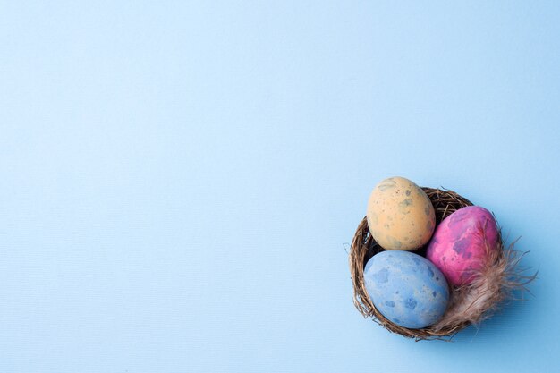 Huevo de Pascua colorido en la jerarquía en fondo azul con el espacio de la copia. Fondo de pascua Minimalismo