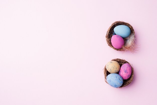 Huevo de Pascua colorido en la jerarquía en fondo rosado con el espacio de la copia. Fondo de pascua Minimalismo