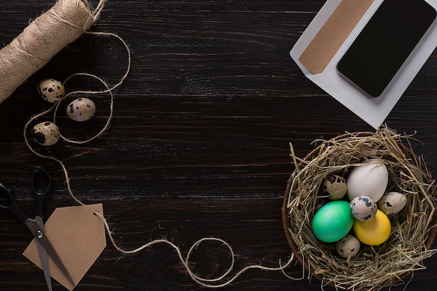 Huevo de pascua colorido en nido en tablero de madera oscura