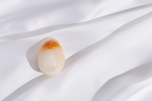Huevo de Pascua decorativo hecho de ónix de piedras preciosas naturales sobre mantel de lino textil. Vacaciones de primavera de moda