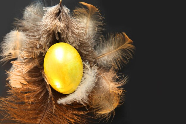 Huevo de Pascua dorado en un nido de plumas.