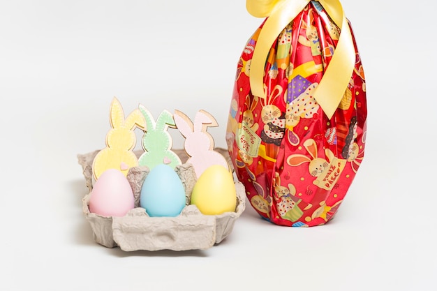 Huevo de Pascua en un hermoso empaque rojo con cinta amarilla y varios pequeños huevos coloridos con conejitos de adorno Aislados en fondo blanco Primer plano