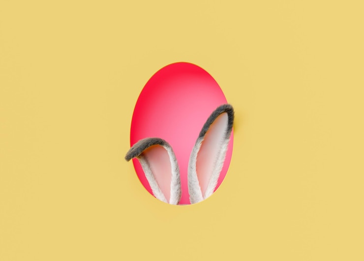 Huevo de Pascua rojo y orejas de conejo contra un fondo amarillo