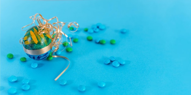 Huevo de Pascua verde y azul y caramelos sobre un fondo azul claro