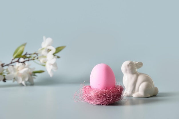 Huevo rosa de pascua y conejito en composición de primavera en azul