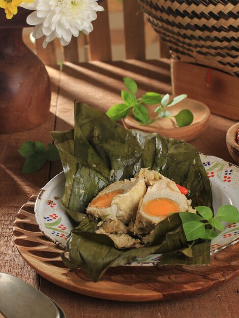 Foto huevo salado al vapor de enfoque seleccionado (pepes telur asin) envuelto con hoja de plátano y adornado con albahaca de limón