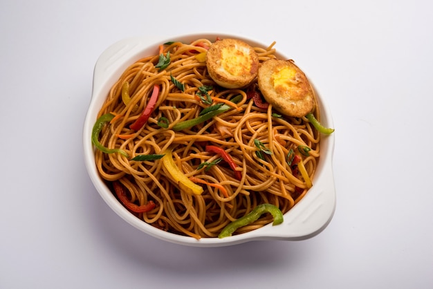 Huevo Schezwan o fideos hakka, comida popular indochina servida en un tazón con palillos