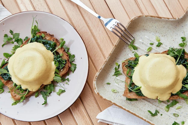 Huevos benedictinos veganos creativos con salsa a base de plantas pan de masa fermentada cebolla joven tofu verduras brotes de guisantes Desayuno saludable para dos personas Vista superior comida