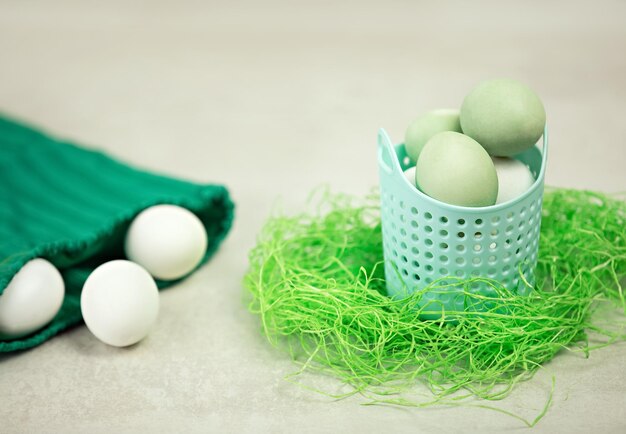 Huevos blancos en una cesta turquesa y bolsa verde sobre fondo blanco.