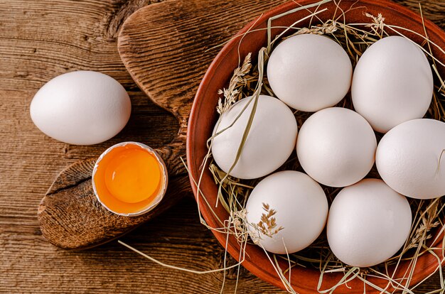 Huevos blancos orgánicos crudos en mesa de madera. Vista superior