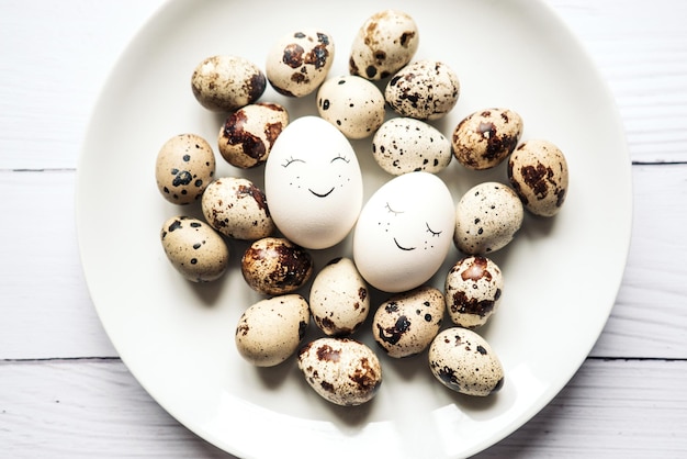 Huevos blancos de pascua y codorniz con una linda sonrisa yacen en un plato sobre un fondo blanco