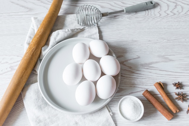 Huevos blancos en un plato con servilleta sobre fondo blanco de madera