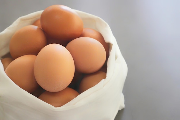 Huevos en una bolsa de tela blanca sobre un fondo gris.