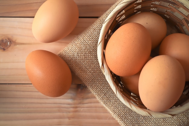 Huevos en la canasta de madera sobre la mesa de madera.