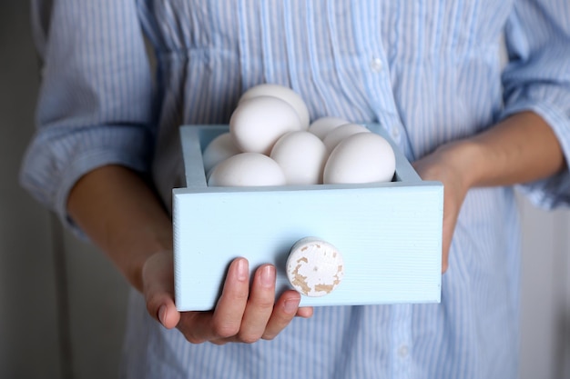 Huevos en canasta en manos de mujeres sobre fondo de madera