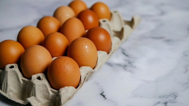 Huevos en cartón de huevos sobre mesa de mármol