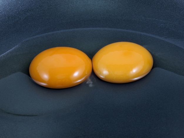 Huevos y cáscara agrietados en una cacerola negra