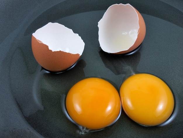 Huevos y cáscara agrietados en una cacerola negra