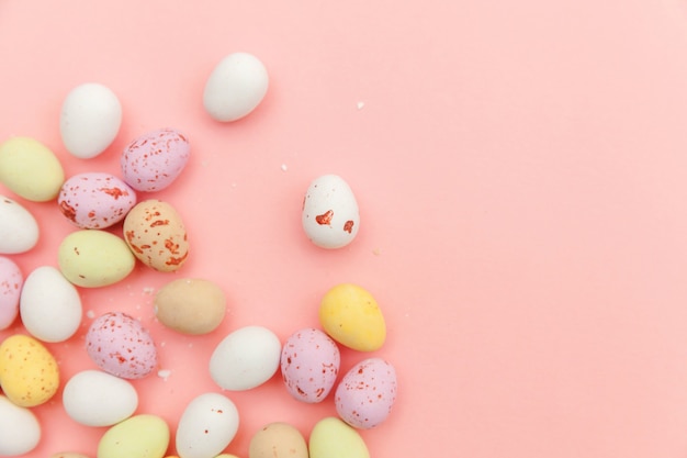 Huevos de chocolate de caramelo de Pascua y dulces de gelatina aislados en mesa rosa