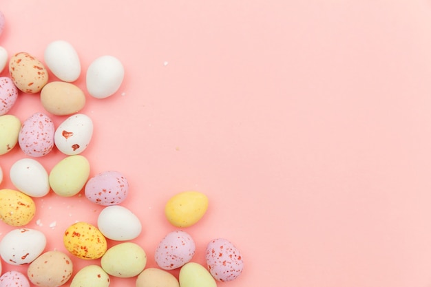 Huevos de chocolate de caramelo de Pascua y dulces de gelatina aislados en mesa rosa