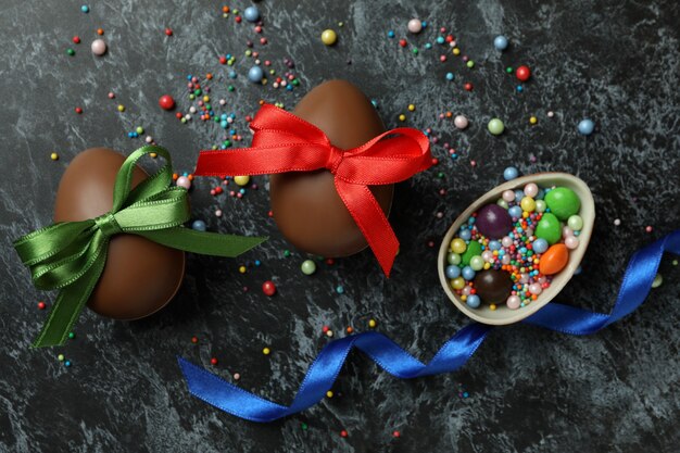 Huevos de chocolate de Pascua con cinta sobre superficie ahumada negra