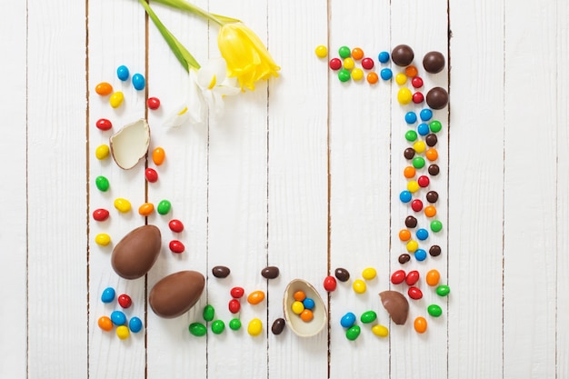 Huevos de chocolate de Pascua y dulces en la superficie de madera blanca